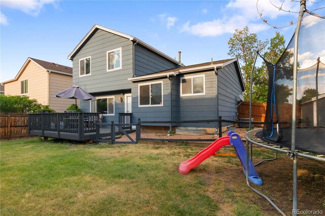 4363 E Andover Ave, Castle Rock, CO 80104 - back of property with a trampoline, a fenced backyard, a wooden deck, and a playground