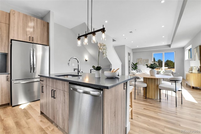 kitchen featuring a sink, a kitchen breakfast bar, stainless steel appliances, modern cabinets, and a kitchen island with sink