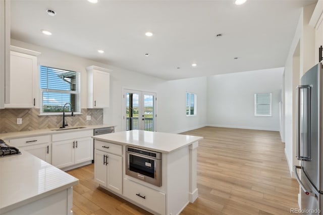 kitchen with tasteful backsplash, light wood finished floors, stainless steel appliances, and a sink