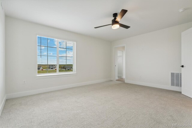 empty room featuring visible vents, light carpet, baseboards, and ceiling fan