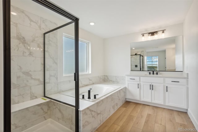 bathroom featuring wood finished floors, a stall shower, vanity, and a bath