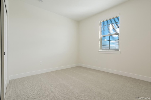 empty room featuring light colored carpet and baseboards