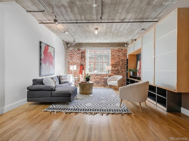 1449 Wynkoop St Unit 305, Denver, CO 80202 - living room featuring brick wall, baseboards, wood finished floors, and track lighting