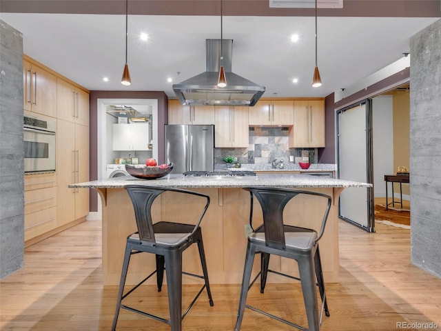 1449 Wynkoop St Unit 305, Denver, CO 80202 - kitchen with stainless steel appliances, light brown cabinetry, island exhaust hood, light wood finished floors, and light stone counters