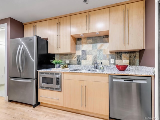 1449 Wynkoop St Unit 305, Denver, CO 80202 - kitchen with appliances with stainless steel finishes, light brown cabinetry, a sink, and light stone counters