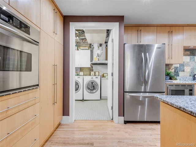 1449 Wynkoop St Unit 305, Denver, CO 80202 - kitchen with stainless steel appliances, independent washer and dryer, light stone counters, and light brown cabinetry