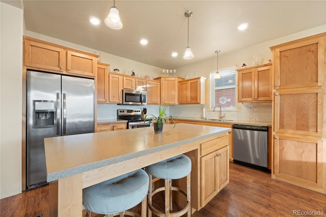 kitchen featuring sink, a center island, hanging light fixtures, dark hardwood / wood-style flooring, and appliances with stainless steel finishes