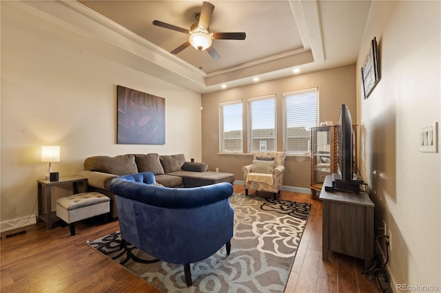 living room with dark hardwood / wood-style floors, ceiling fan, and a tray ceiling