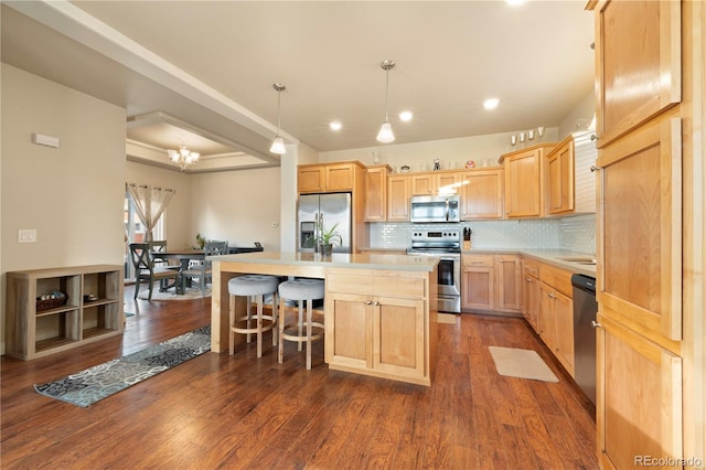 kitchen with light brown cabinets, hanging light fixtures, stainless steel appliances, dark hardwood / wood-style flooring, and an island with sink