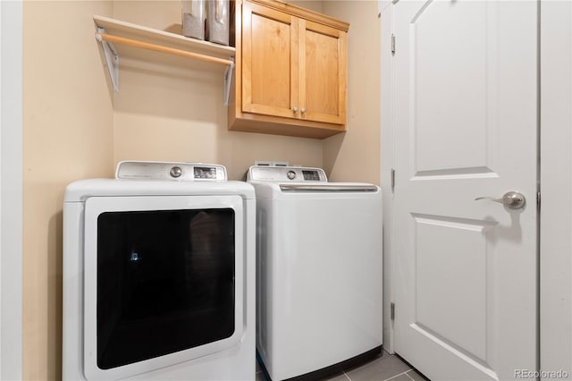 washroom with washing machine and dryer, light tile patterned floors, and cabinets