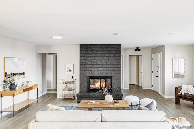 living area with baseboards, wood finished floors, and a fireplace