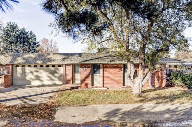 ranch-style home featuring brick siding, roof with shingles, concrete driveway, and an attached garage