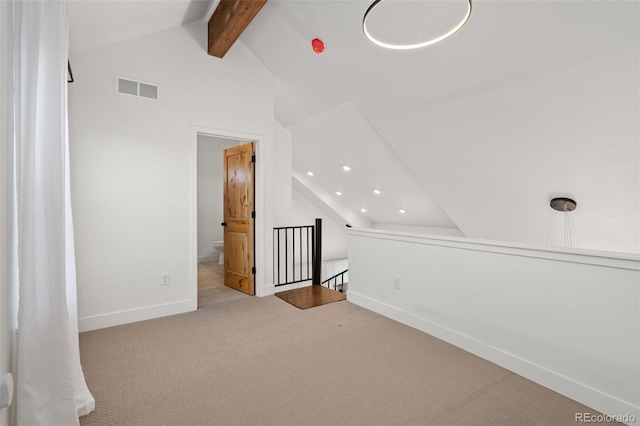 additional living space featuring lofted ceiling with beams and light carpet