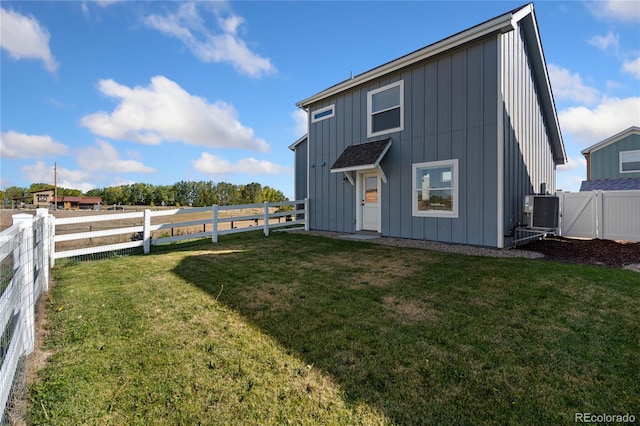 back of property with a yard and central AC unit