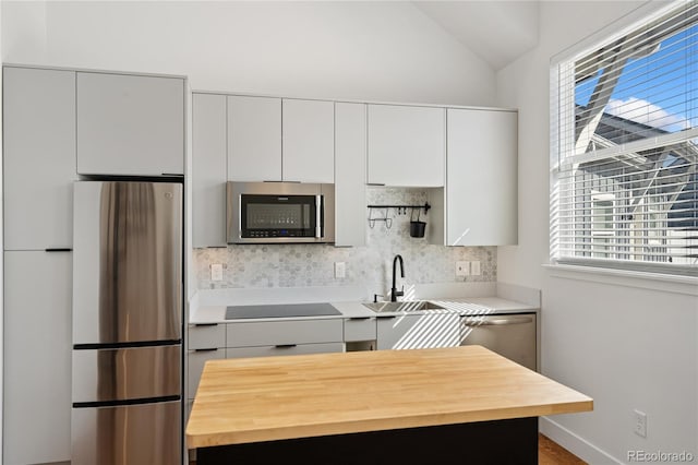 kitchen featuring white cabinetry, appliances with stainless steel finishes, vaulted ceiling, and a wealth of natural light