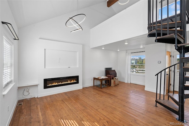 living room featuring beamed ceiling, hardwood / wood-style flooring, a chandelier, and high vaulted ceiling