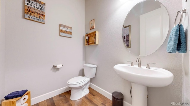 bathroom featuring a sink, toilet, baseboards, and wood finished floors