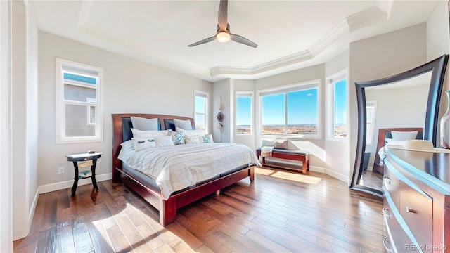 bedroom with wood-type flooring, baseboards, a raised ceiling, and ornamental molding