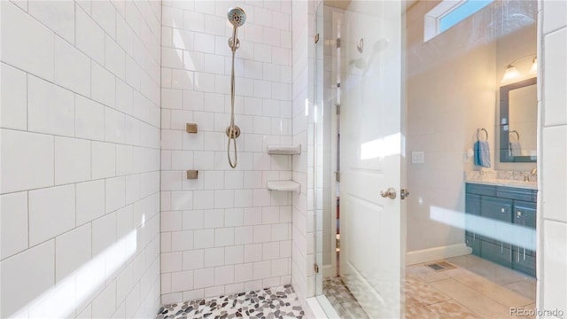 full bathroom with tile patterned floors, visible vents, a tile shower, and vanity