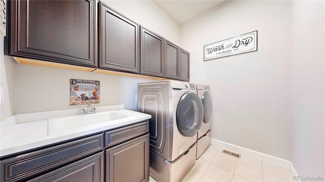 washroom with light tile patterned floors, separate washer and dryer, a sink, baseboards, and cabinet space