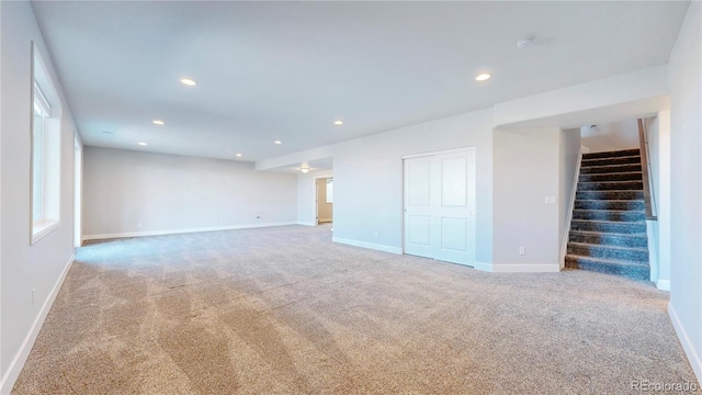 carpeted empty room with baseboards, stairway, and recessed lighting