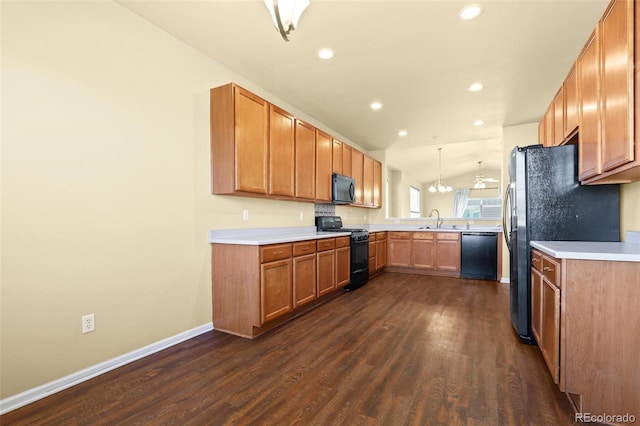 kitchen featuring dark wood-style flooring, lofted ceiling, light countertops, a sink, and black appliances