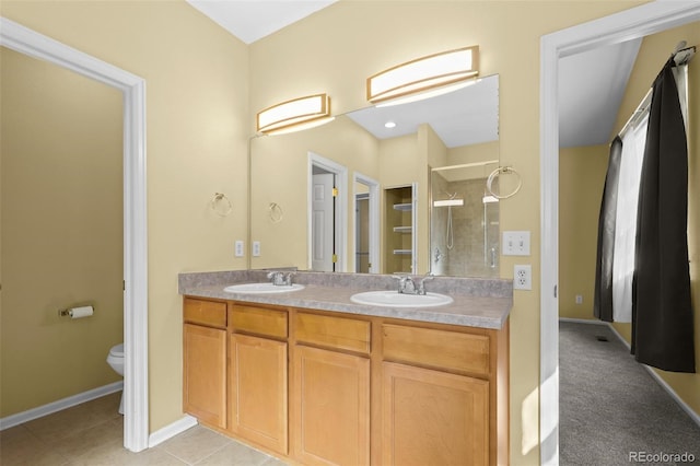 bathroom featuring double vanity, a stall shower, a sink, and toilet