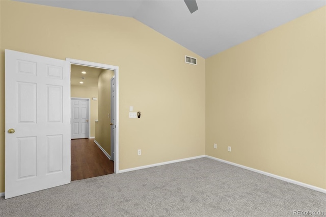 carpeted spare room featuring lofted ceiling, baseboards, visible vents, and ceiling fan