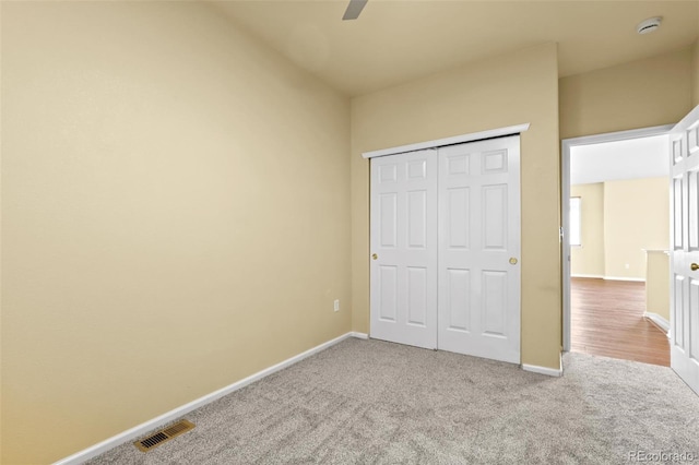 unfurnished bedroom featuring ceiling fan, visible vents, baseboards, a closet, and carpet