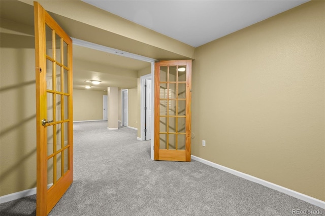 carpeted spare room featuring baseboards and french doors