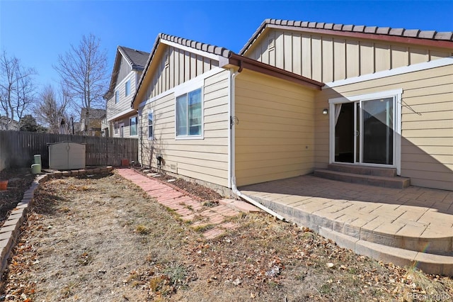 rear view of property featuring board and batten siding, a patio area, and a fenced backyard