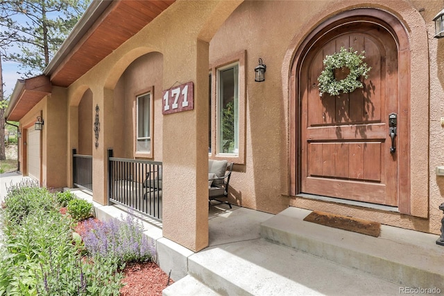 171 Columbine St, Larkspur, CO 80118 - property entrance with a porch, stucco siding, and an attached garage