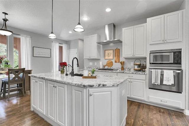 171 Columbine St, Larkspur, CO 80118 - kitchen with stainless steel appliances, wall chimney range hood, white cabinets, an island with sink, and recessed lighting