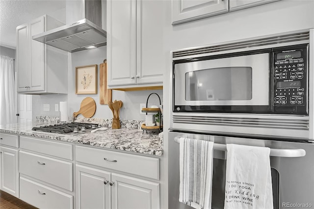 171 Columbine St, Larkspur, CO 80118 - kitchen featuring wall chimney range hood, stainless steel appliances, white cabinets, and light stone countertops