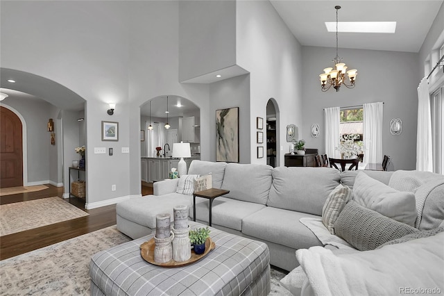 171 Columbine St, Larkspur, CO 80118 - living room featuring arched walkways, high vaulted ceiling, a chandelier, and dark wood-style flooring