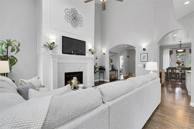 171 Columbine St, Larkspur, CO 80118 - living area with arched walkways, ceiling fan, a high ceiling, dark wood-style floors, and a fireplace