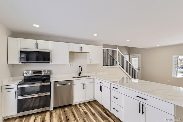 kitchen featuring sink, stainless steel appliances, kitchen peninsula, and white cabinets