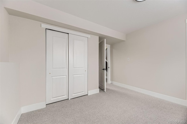 unfurnished bedroom with light carpet and a closet