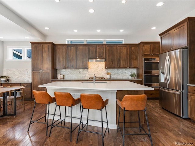 5511 Wabash St, Denver, CO 80238 - kitchen with stainless steel appliances, under cabinet range hood, backsplash, a sink, and dark wood-type flooring