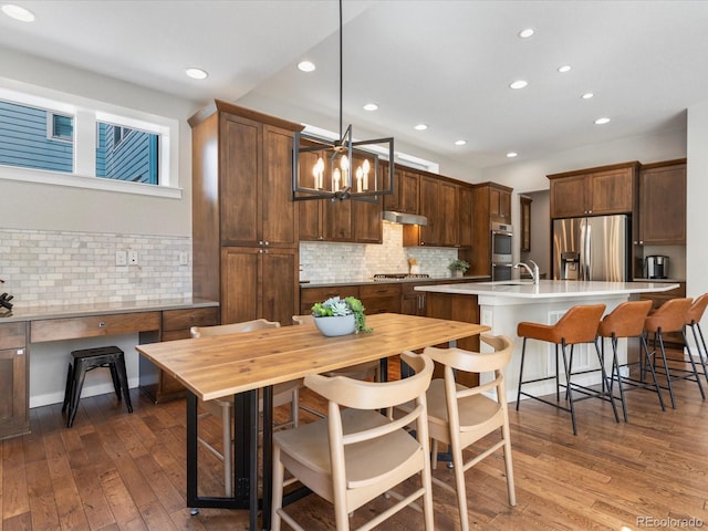 5511 Wabash St, Denver, CO 80238 - kitchen featuring stainless steel appliances, dark wood-type flooring, an island with sink, recessed lighting, and decorative backsplash