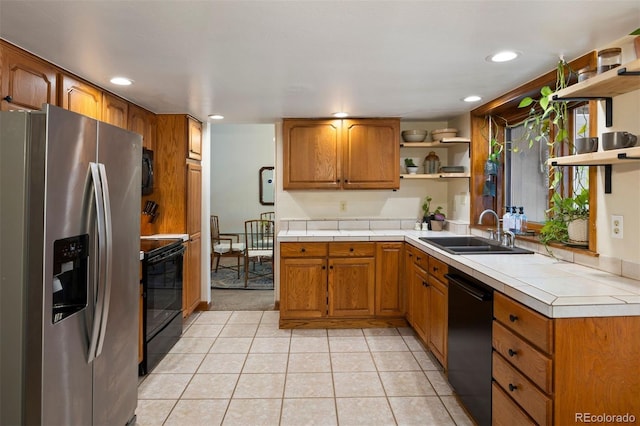 kitchen with sink, tile countertops, black appliances, and light tile patterned floors