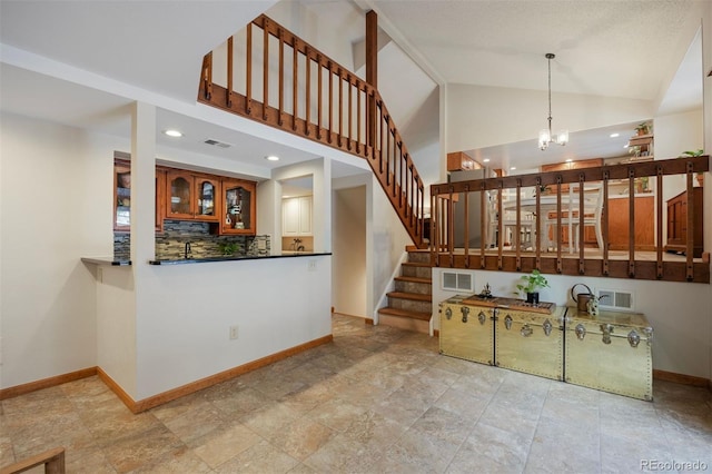 kitchen featuring a notable chandelier, hanging light fixtures, vaulted ceiling, and decorative backsplash