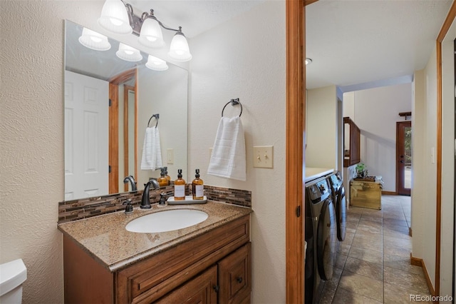 bathroom with toilet, vanity, decorative backsplash, and separate washer and dryer