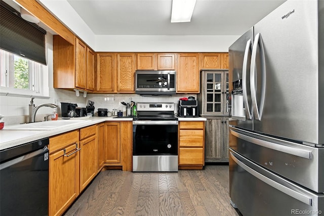 4604 Routt St, Wheat Ridge, CO 80033 - kitchen featuring stainless steel appliances, wood finished floors, light countertops, backsplash, and brown cabinetry