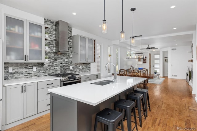 3932 Utica St, Denver, CO 80212 - kitchen featuring a sink, gas stove, gray cabinetry, and wall chimney exhaust hood