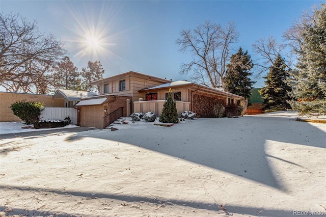 view of front of property with a garage, brick siding, fence, and driveway