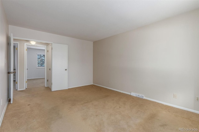 spare room with baseboards, visible vents, and light colored carpet