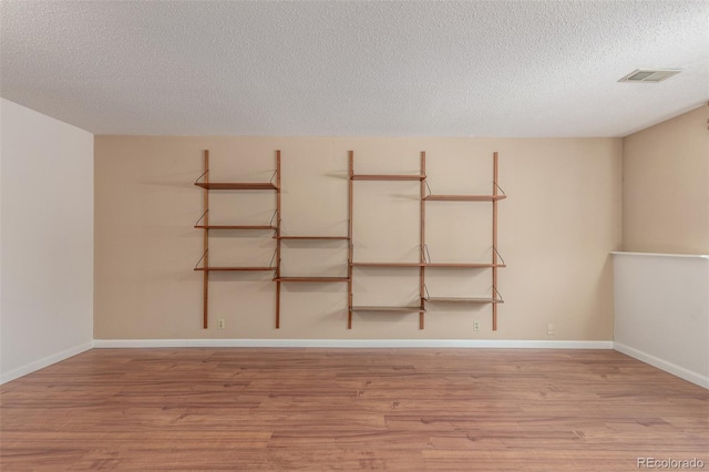 unfurnished room featuring light wood-style floors, visible vents, and baseboards