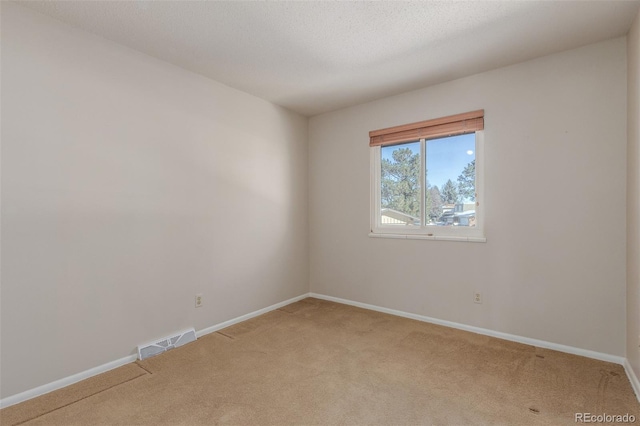 empty room with visible vents, light carpet, baseboards, and a textured ceiling