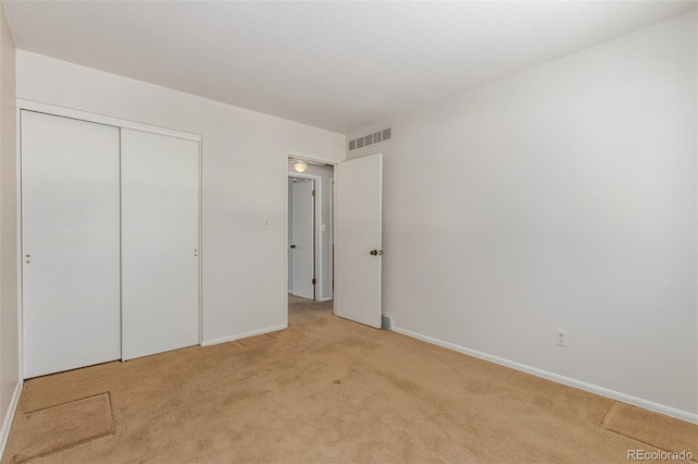 unfurnished bedroom with light carpet, baseboards, visible vents, and a closet